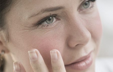 Žena sa rukou dotýka tváre