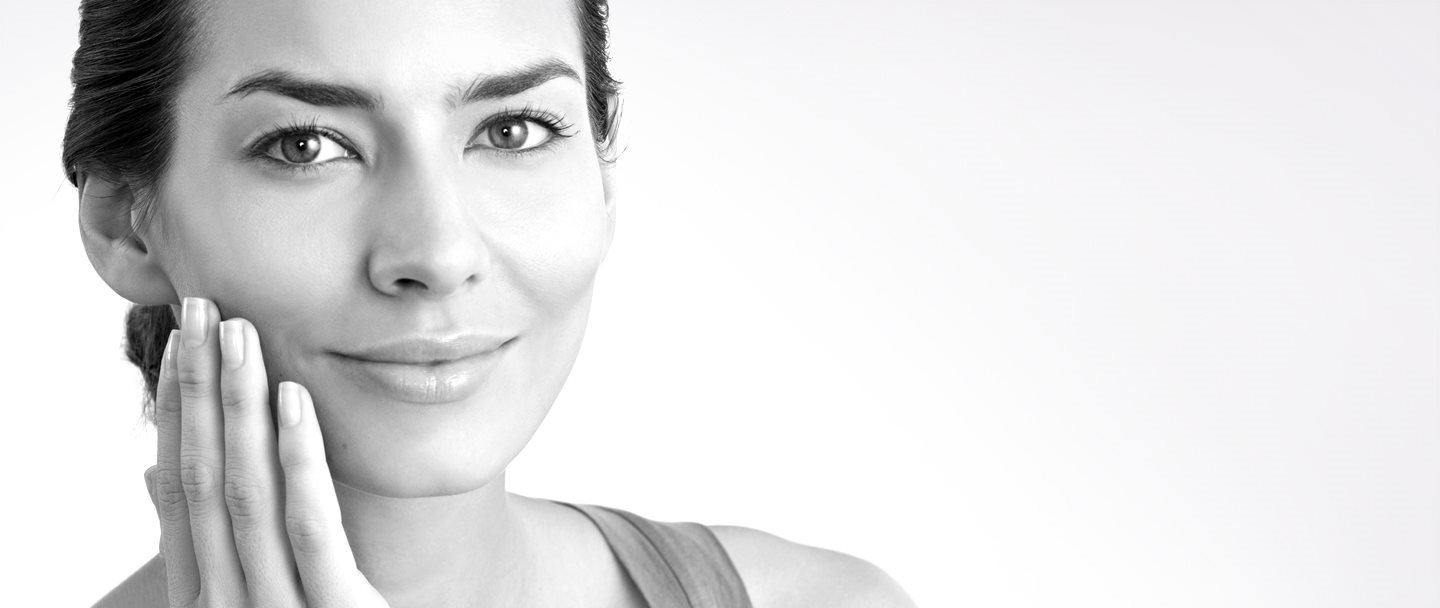 Žena v stredných rokoch sa rukou dotýka pravého líca