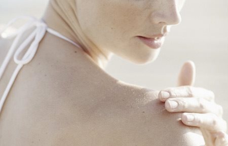 Žena aplikujúca krém na pravé rameno